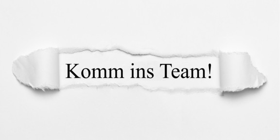 Komm ins Team! Text hinter einem Papierausriss