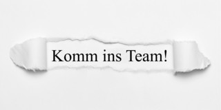 Komm ins Team! Text hinter einem Papierausriss